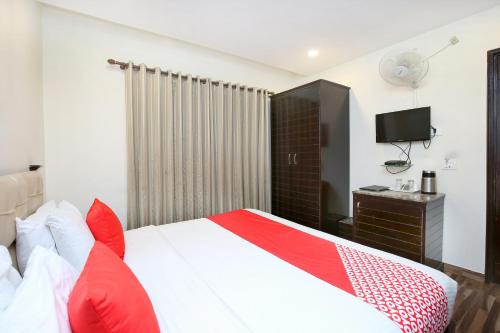 a bedroom with a red and white bed and a television at Akashdeep 22 in Chandīgarh