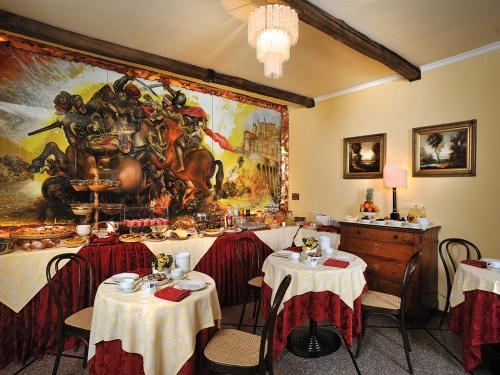 a restaurant with tables and a large painting on the wall at Hotel Bonconte in Urbino