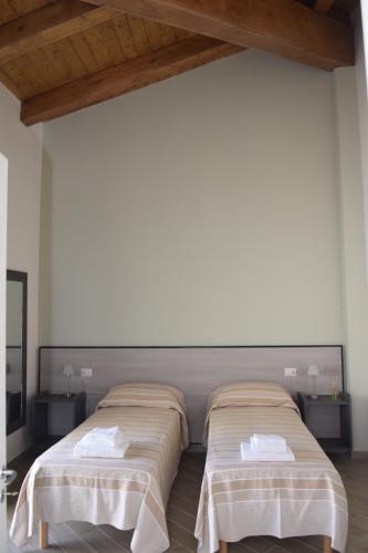 two beds in a room with white walls and wooden ceilings at La Formica in Civitavecchia