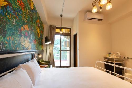 a bedroom with a bed with a large painting on the wall at Love Inn in Hualien City