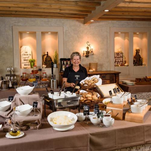 Schlosshotel Steinburg في فورتسبورغ: امرأة تقف خلف المنضدة مع أوعية الطعام