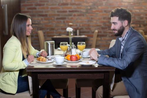 a man and a woman sitting at a table with food at Boutique Hotel Sopianae in Pécs