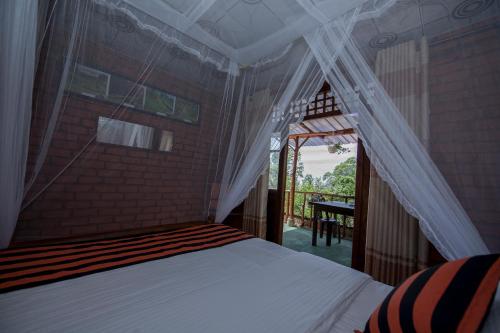 a bedroom with a bed with a canopy and a table at Apurvi Homestay in Ella