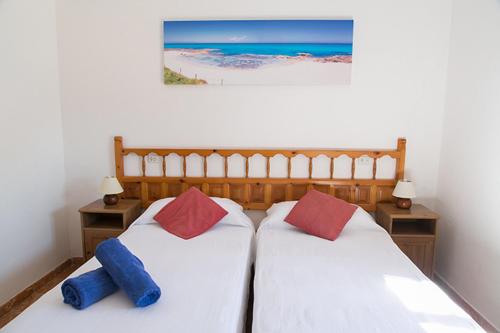 two beds in a bedroom with a picture of the beach at Ca Na Maria Teueta in San Ferrán de ses Roques