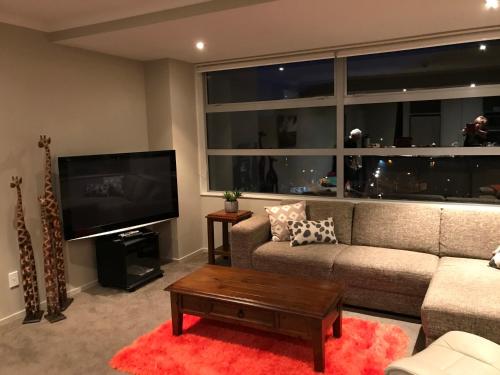 a living room with a couch and a flat screen tv at Astonishing Views Superb Waterfront Apartment in Picton