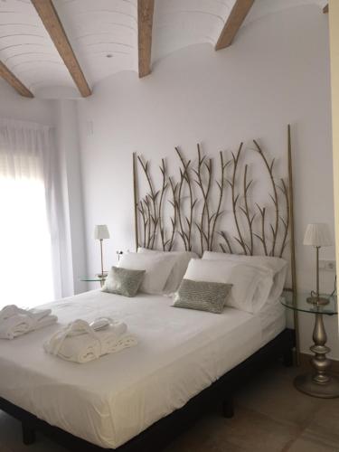 a bedroom with a large white bed with plants on the wall at Casa Boquera in Carche