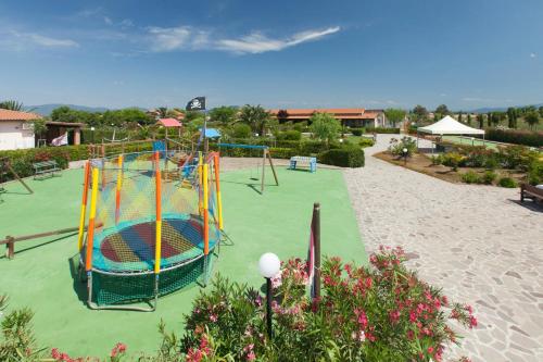 a playground with a trampoline on a green lawn at Fattoria Maremmana in Marina di Grosseto
