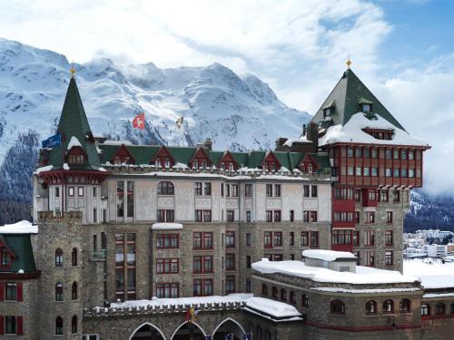 a large building with snowy mountains in the background at Badrutt's Palace Hotel St Moritz in St. Moritz
