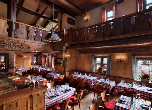 a restaurant with tables and chairs in a room at Badrutt's Palace Hotel St Moritz in St. Moritz