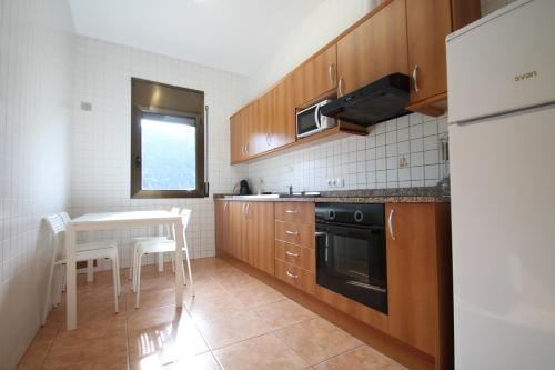a kitchen with wooden cabinets and a table with chairs at Pont de Toneta 4,4 Ransol, Zona Grandvalira in Ransol