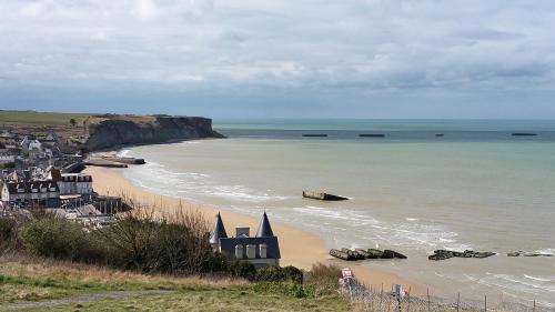a view of a beach with a house and the ocean at Château Baffy in Colombiers-sur-Seulles
