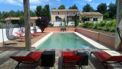 une piscine avec des chaises et une table ainsi qu'une maison dans l'établissement Domaine de Villemus, à Jouques