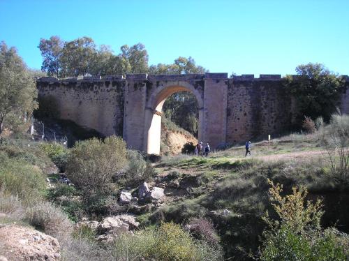 an old stone bridge with people walking under it at Hotel & Spa PLAZA Arriate in Arriate