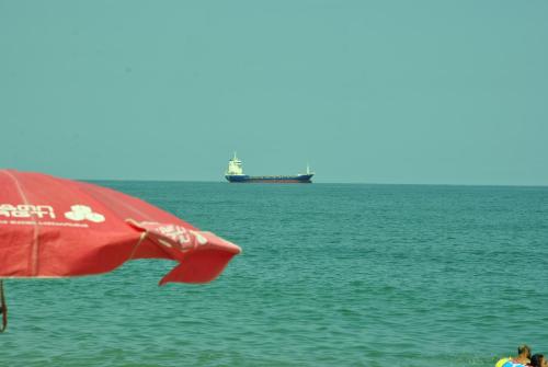 a red umbrella and a ship in the ocean at the View Apartment in Makhinjauri