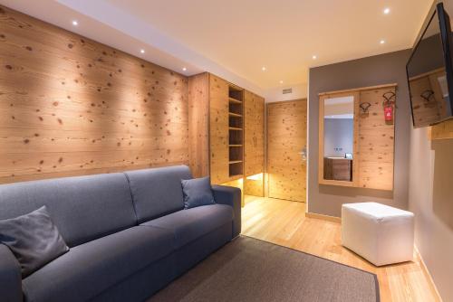 a living room with a blue couch and wooden walls at Hotel Astoria in Livigno