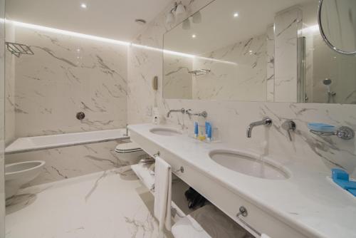 a white bathroom with a sink and a mirror at Gallia Palace Hotel - Relais & Châteaux in Punta Ala