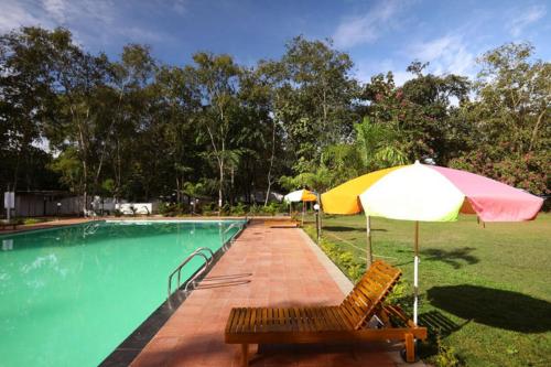 a pool with two chairs and an umbrella and a table at Nature Trails Sajan, Vikramgad in Kudān