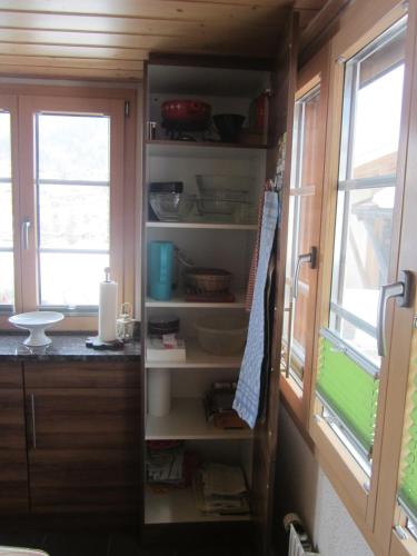 an open pantry in a kitchen with two windows at Chalet Bärgblick in Grindelwald