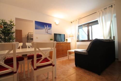 a living room with a table and chairs and a television at Pont de Toneta 6,2 Ransol, Zona Grandvalira in Ransol