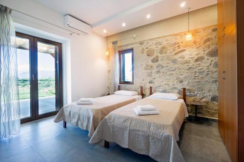 2 łóżka w pokoju z kamienną ścianą w obiekcie Iridanos Villa w mieście Kisamos