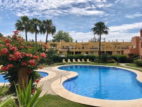 マルベーリャにあるApartamento Guadalmina - Golf & Playa - Marbellaのヤシの木と花が咲くリゾート内のスイミングプール