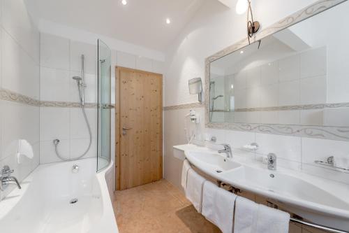 a bathroom with a tub and a sink and a shower at Hotel Grauer Bär in Sölden