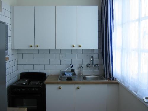 a kitchen with white cabinets and a sink and a stove at Jetty Self-Catering in Swakopmund