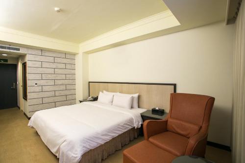 a hotel room with a bed and a chair at Huang Shin Business Hotel-Shang An in Taichung