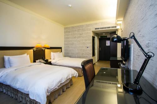 a hotel room with two beds and a glass table at Huang Shin Business Hotel-Shang An in Taichung