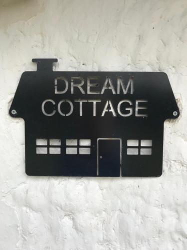 una señal negra en una pared con las palabras "cabaña de ensueño" en Dream Cottage en Ballintober