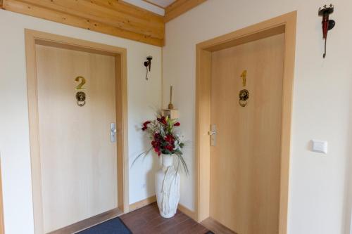 a hallway with two doors and a vase of flowers at Hotel & Restaurant Wilder Eber in Eberswalde-Finow