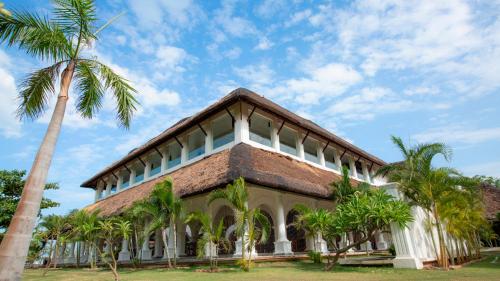 a building with a palm tree in front of it at Le Pondy in Puducherry