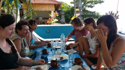 un grupo de personas sentadas alrededor de una mesa en De Adema Guesthouse, en Amed