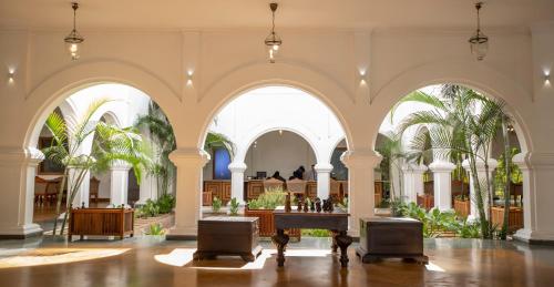 a large building with arches and palm trees at Le Pondy in Puducherry