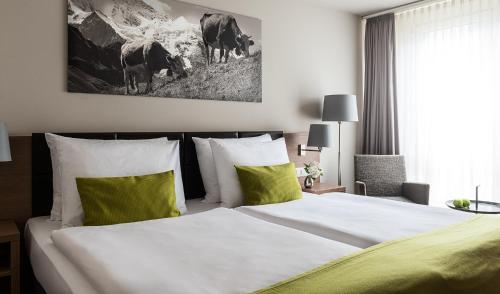 a bedroom with a large bed with green and white pillows at AMERON Luzern Hotel Flora in Luzern