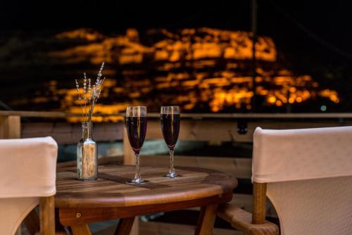 two glasses of wine on a wooden table in front of a fireplace at Ageliki Studio in Matala