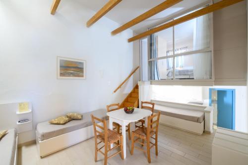 a living room with a table and chairs and a bed at Captain's House Hotel Suites & Apartments in Panormos Rethymno