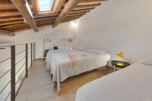 Sarpi Loft Florence في فلورنسا: غرفة نوم بيضاء بسريرين وسقف خشبي