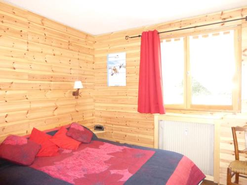a bedroom with wooden walls and a bed with red pillows at Les Seolanes Pra Loup 520 in Pra-Loup