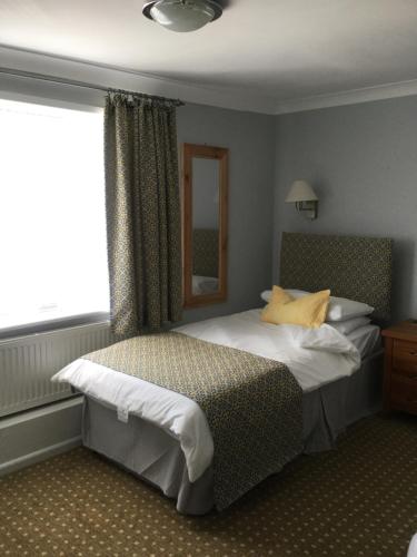 a bedroom with a bed and a window at The Haymaker Inn in Chard