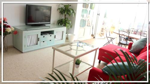 a living room with a television and a red couch at Casa Las Toro Playa in Chilches