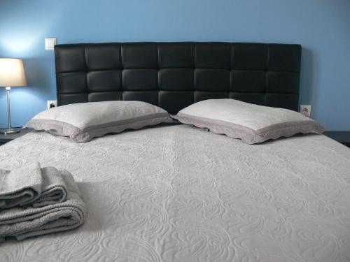 a large bed with a black headboard and two pillows at Eleni Apartments in Preveza