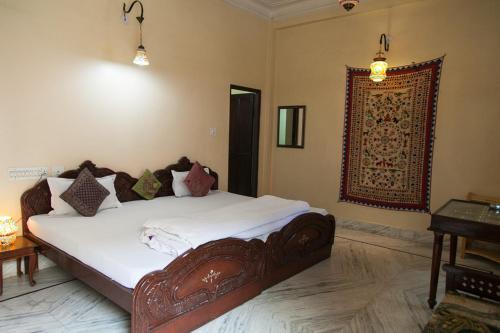 a bedroom with a large bed with white sheets at Kanhaia Haveli in Pushkar