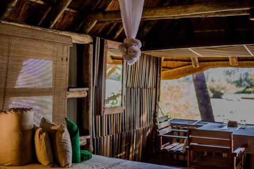 um quarto com uma cama, uma mesa e uma janela em Epupa Falls Lodge em Epupa