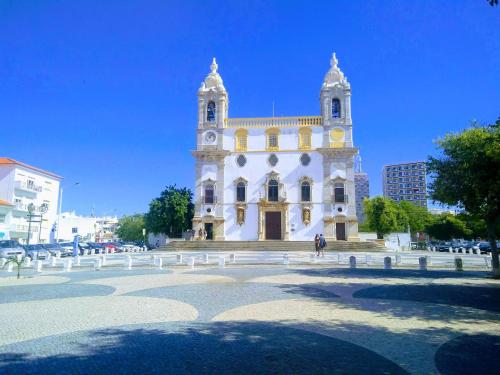 ein großes weißes Gebäude mit einem Uhrturm in der Unterkunft Melaya Budget Hostel in Faro