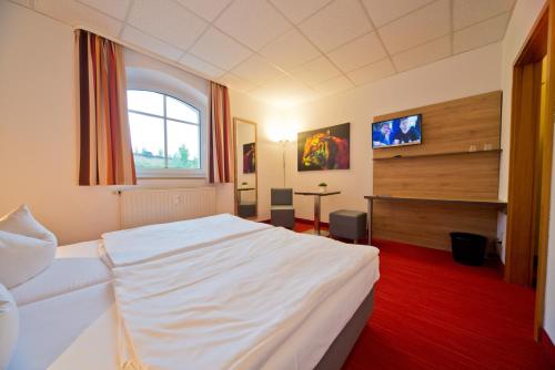 a bedroom with a white bed and a window at City Hotel in Chemnitz
