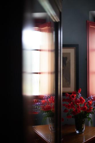 a mirror reflecting two vases with flowers on a table at La Canonica Di Nusenna in Gaiole in Chianti