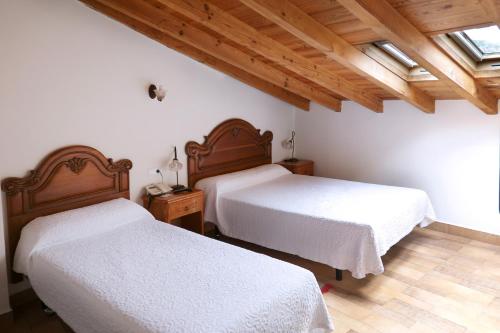 two beds in a room with wooden ceilings at Hotel Rural La Puebla in Orbaneja del Castillo