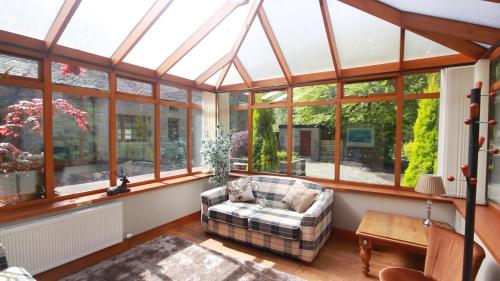 a conservatory with a couch in a room with windows at Smiddy Lodge in Balloch