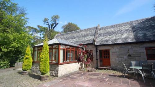 a stone house with a conservatory and a patio at Smiddy Lodge in Balloch